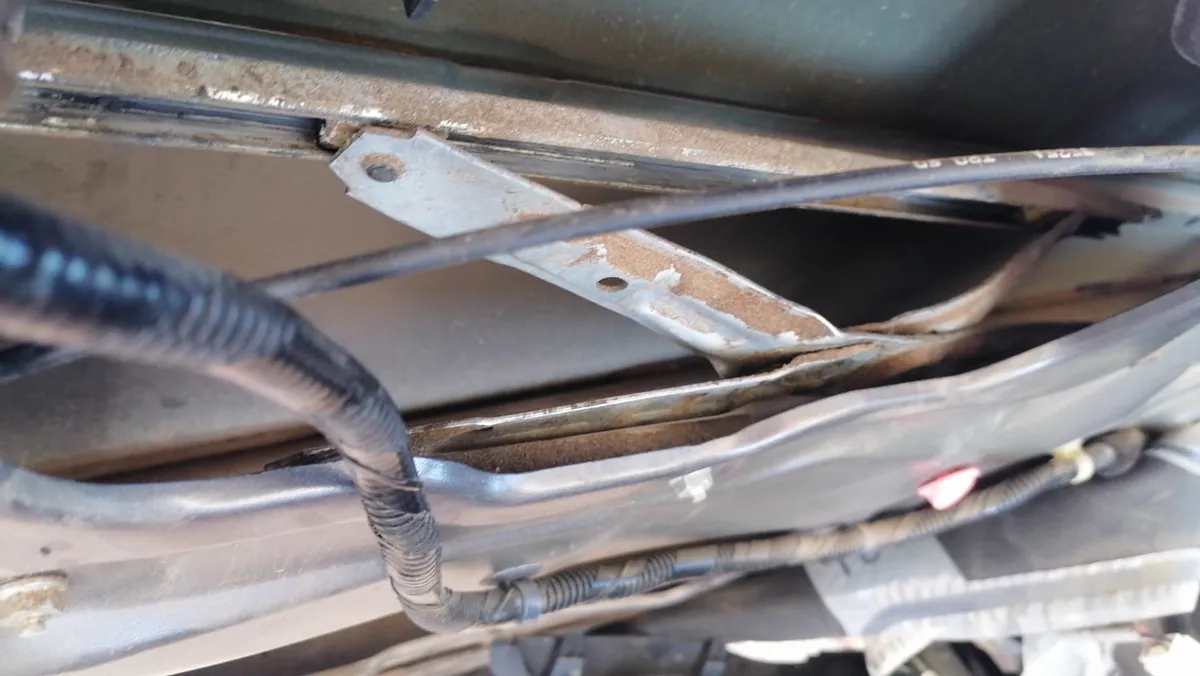 Brazo del elevador de tijera oxidado y torcido dentro de la puerta del Honda Civic