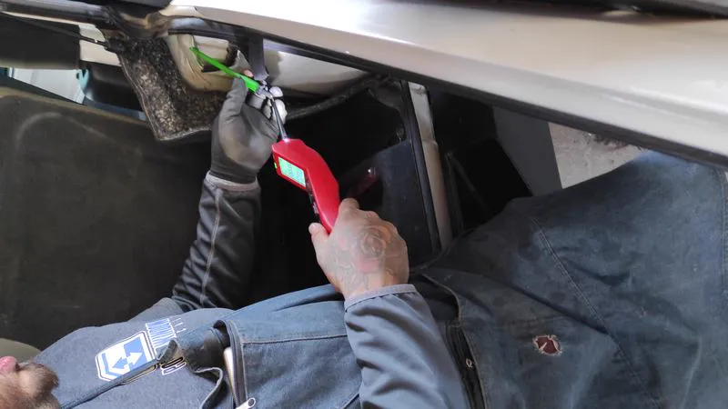 Técnico de Power Window Mexicali revisando la corriente con un probador bajo el tablero